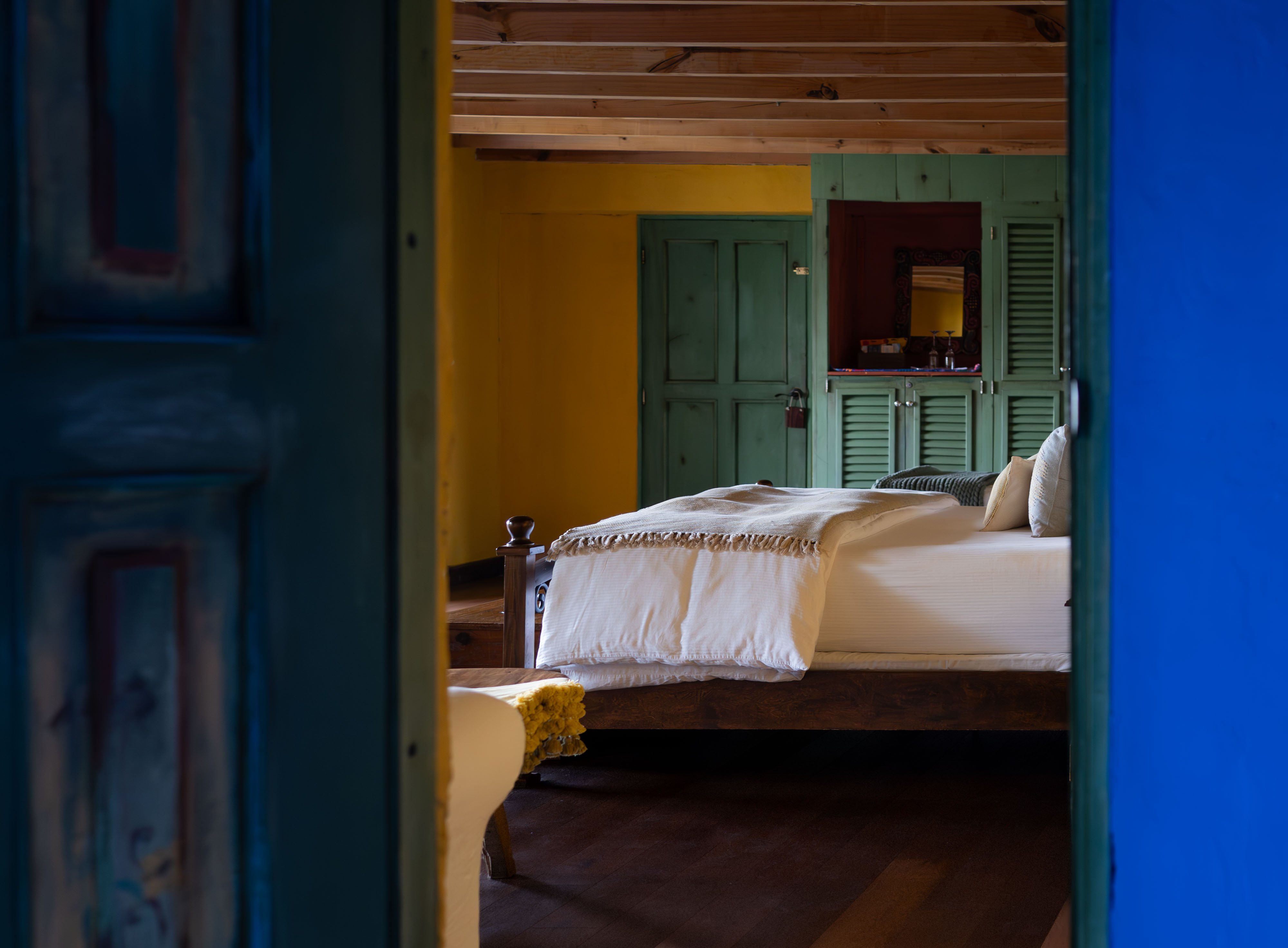 Colorful Casa Palopó guest room framed by blue doors and green shutters