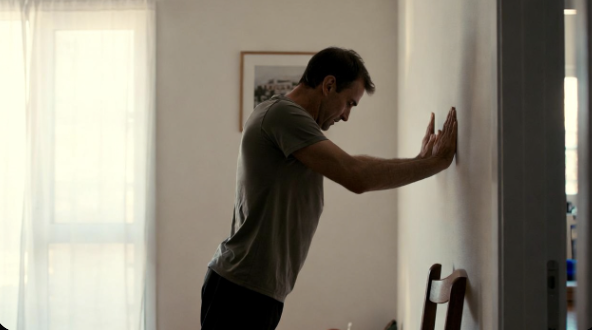 Man doing wall push-ups in a living room