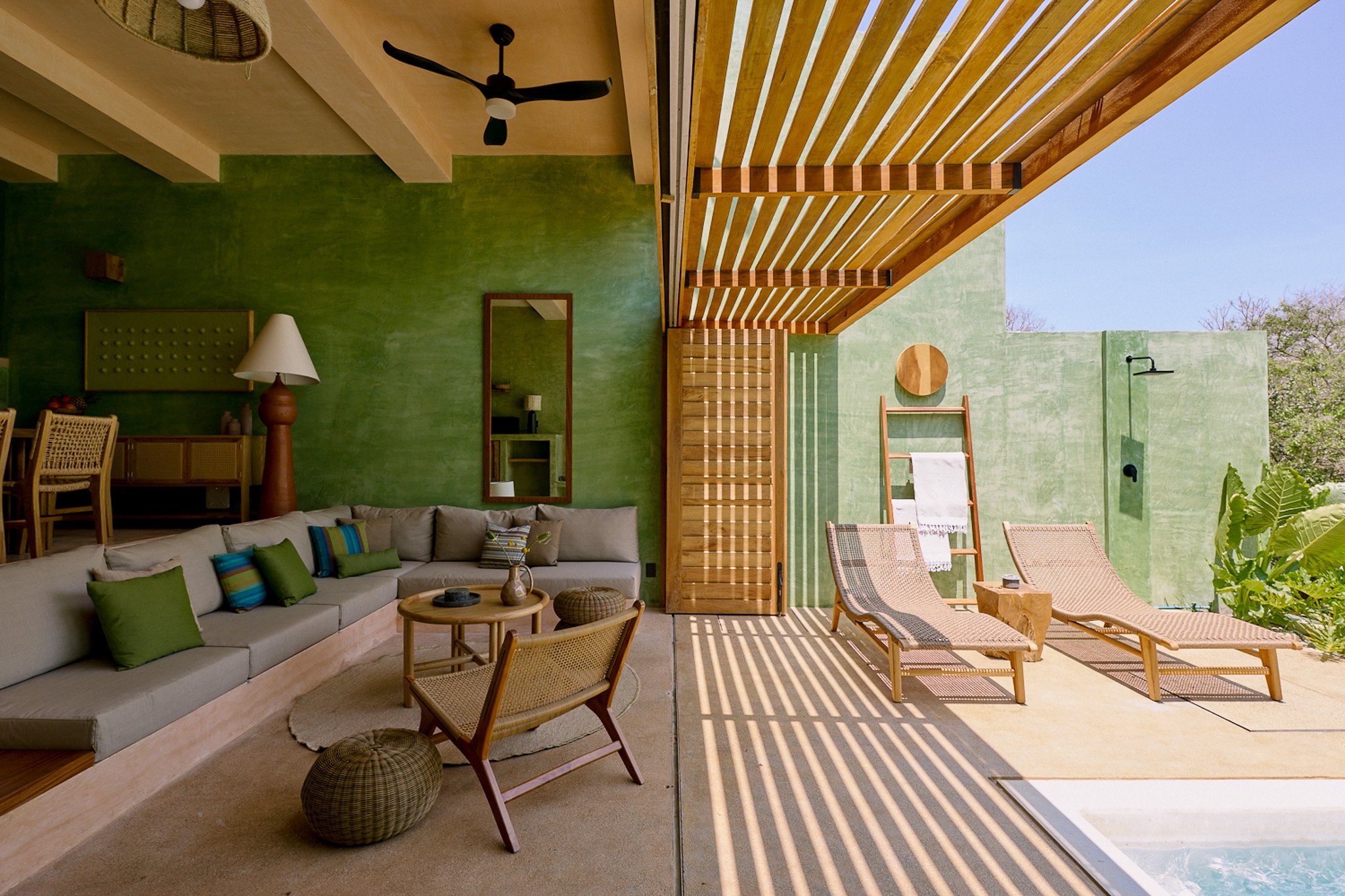 Open-air lounge with mint-green walls and a slatted canopy at Punta Nayaá