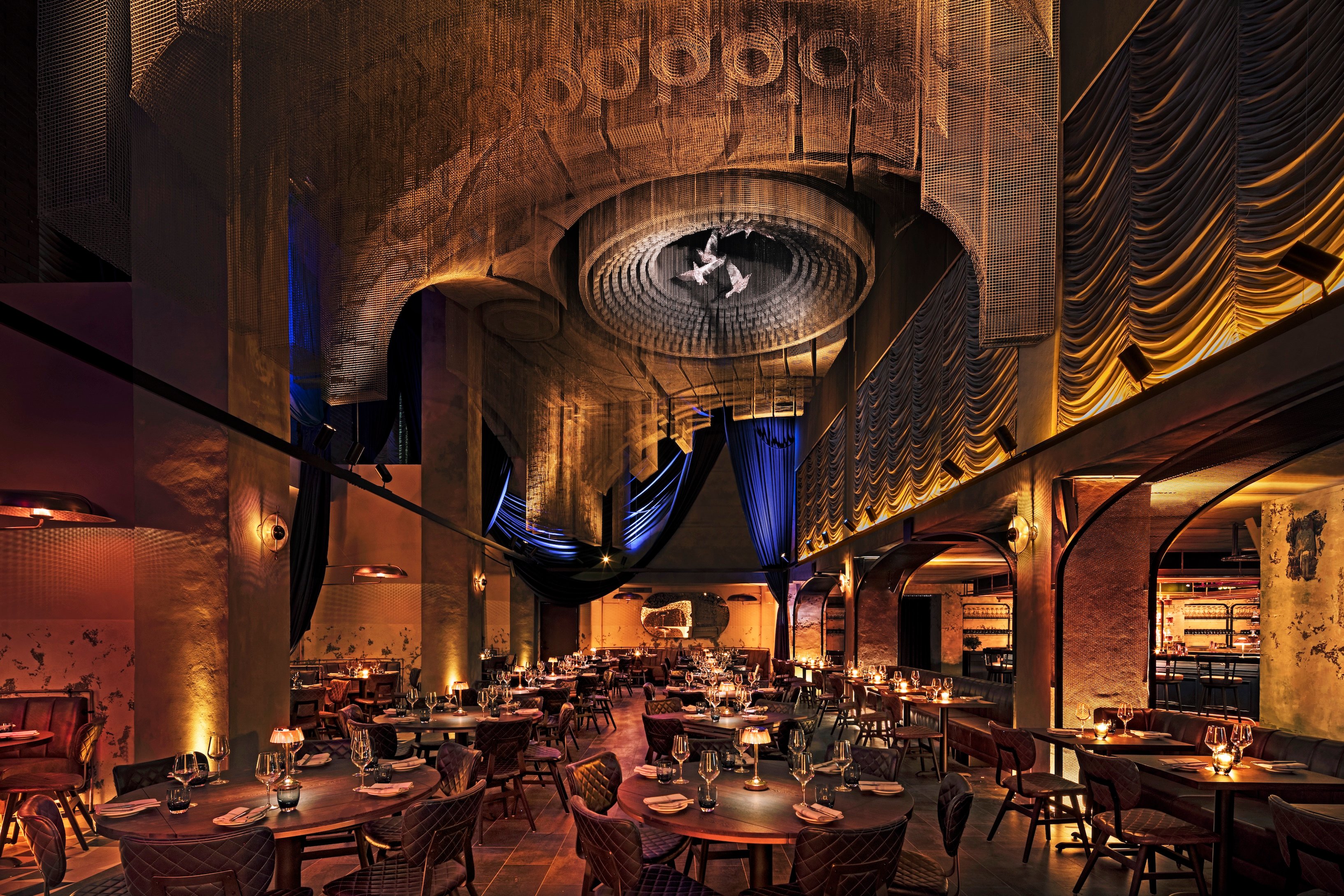 Soaring restaurant dining room beneath a suspended wire-mesh dome