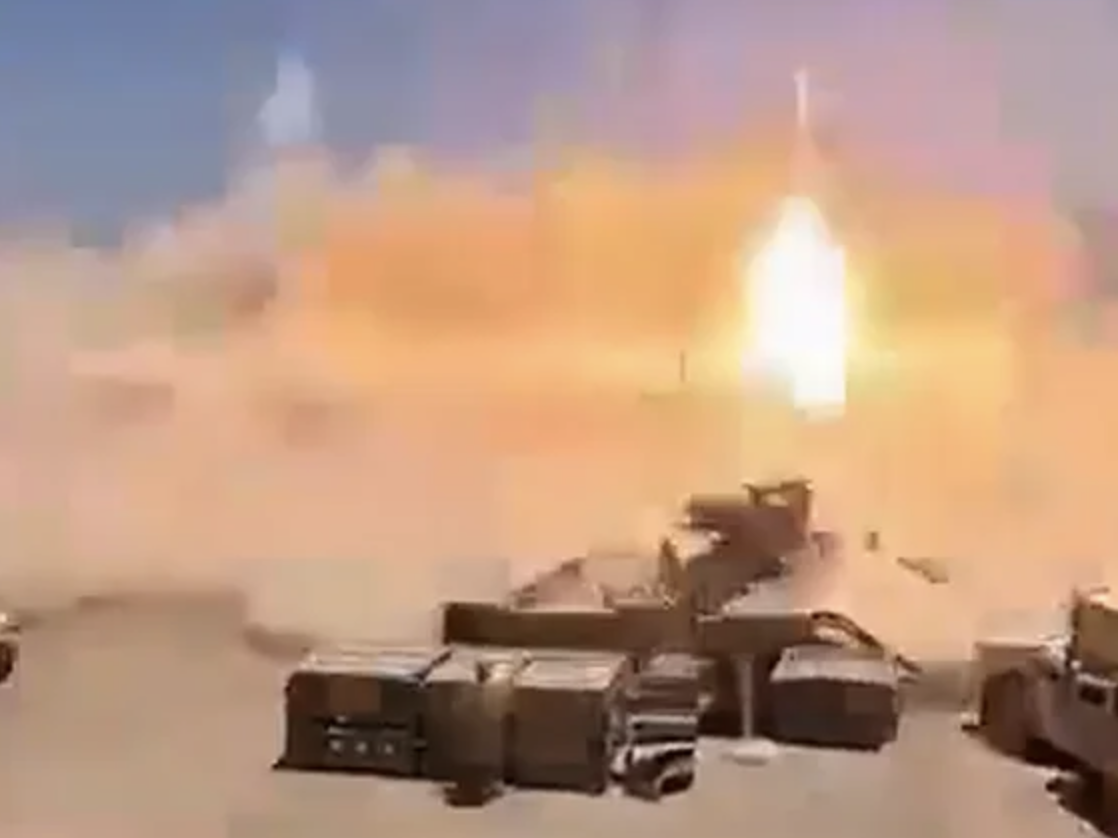 A military base engulfed in flames that never actually happened, rendered like a video game cutscene