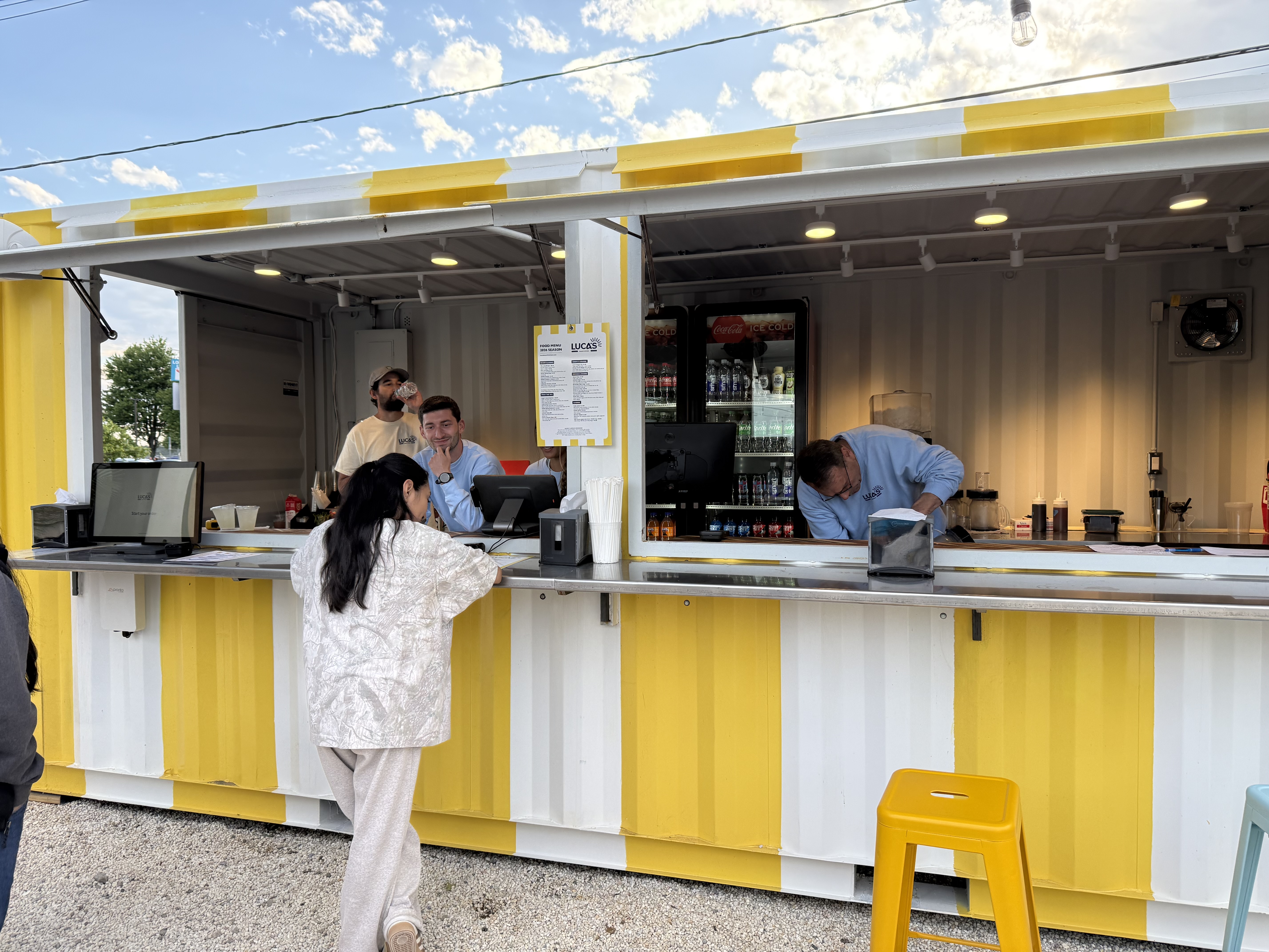 Service window at the Luca's Beach Kitchen drinks container, staff working behind the counter.