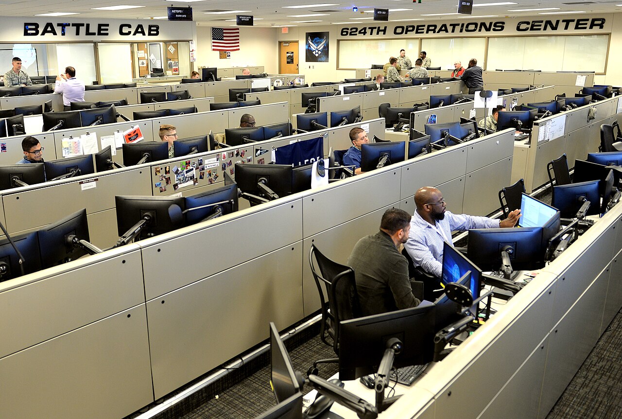 Airmen at rows of computer workstations on the operations floor of the 624th Operations Center, Joint Base San Antonio-Lackland, Texas.