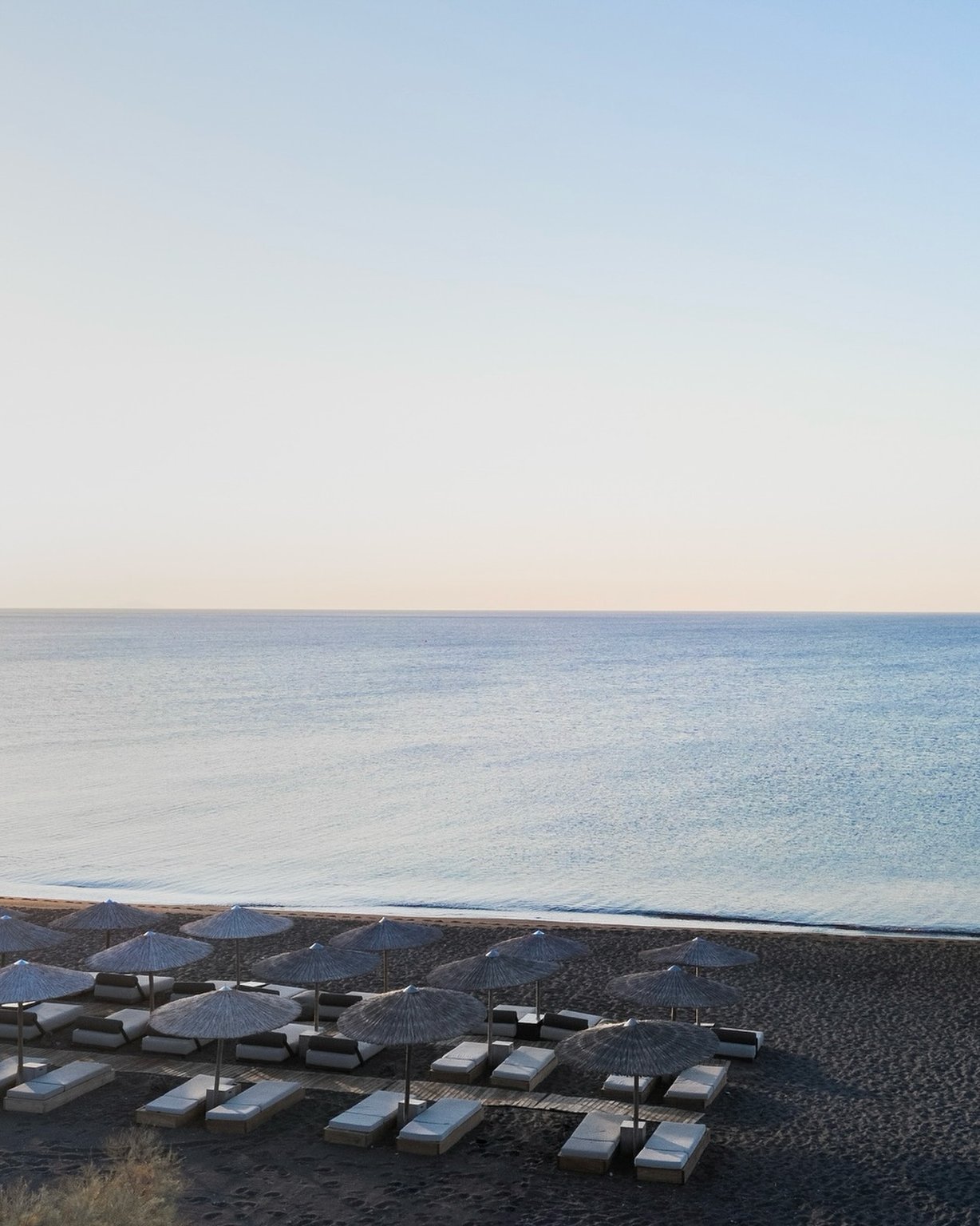 Sunbeds and umbrellas on the black sand beach at Istoria