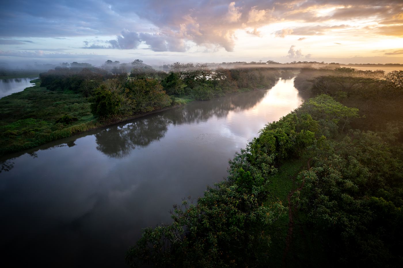 A lowland river at sunset, mist over the water and forest on both banks