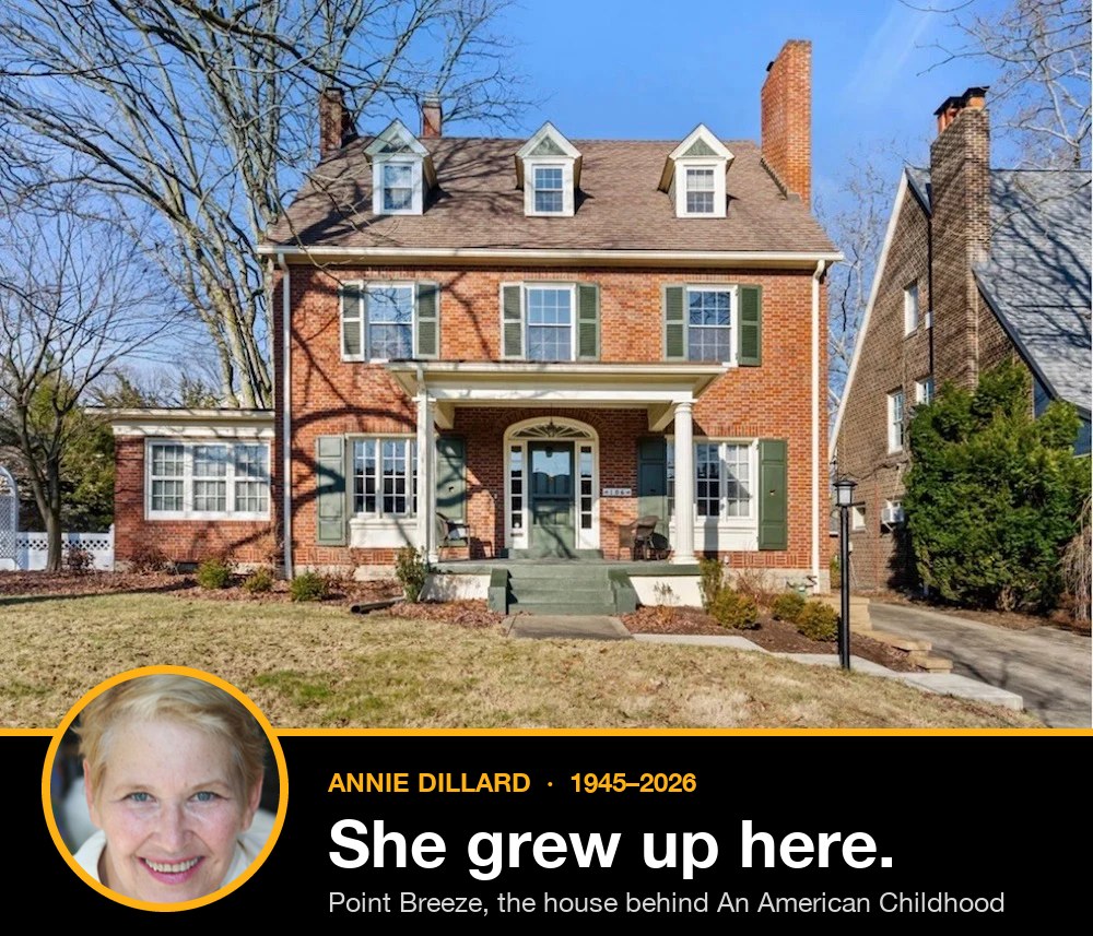 Annie Dillard's childhood home in Point Breeze, a red-brick Colonial with green shutters, three dormers and a columned front porch. A circular inset portrait of Dillard, smiling, sits on a black band that reads: Annie Dillard, 1945 to 2026. She grew up here.