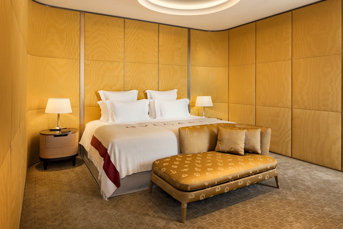 Bvlgari Hotel Roma guest room with warm golden walls and a leather bench