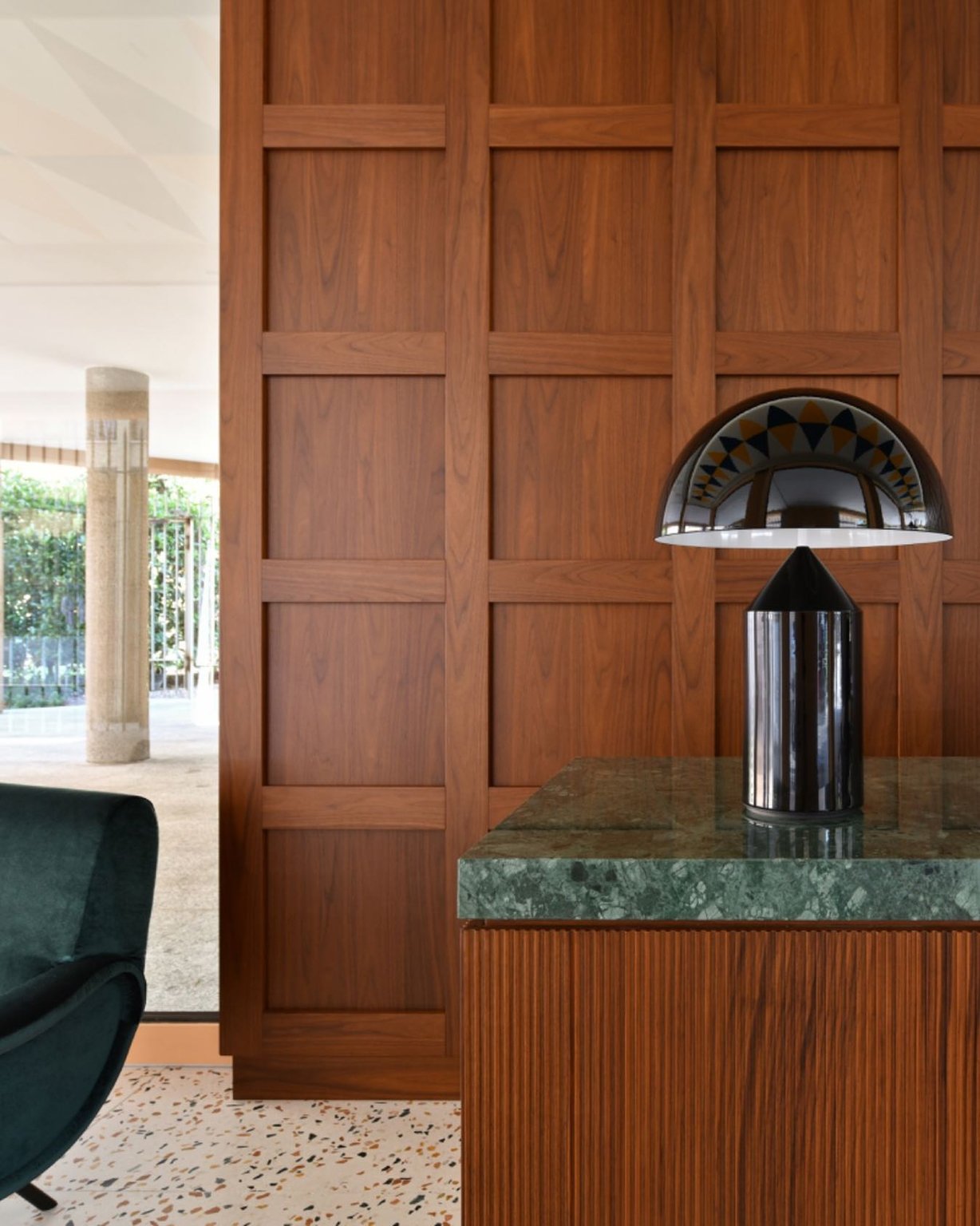 Wood paneling, green marble, and a sculptural lamp at Casa Brivio