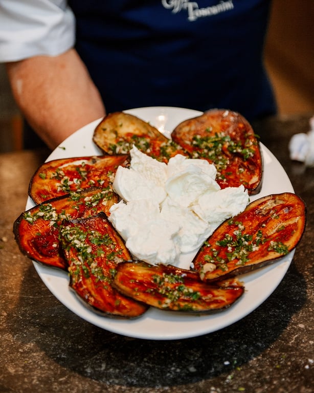 Chef presenting a plated tomato and burrata dish