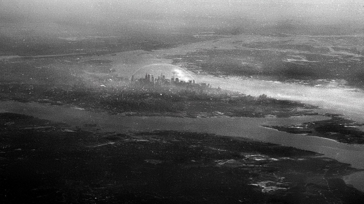 A grainy black and white aerial photo of Manhattan with a glass dome over the skyline