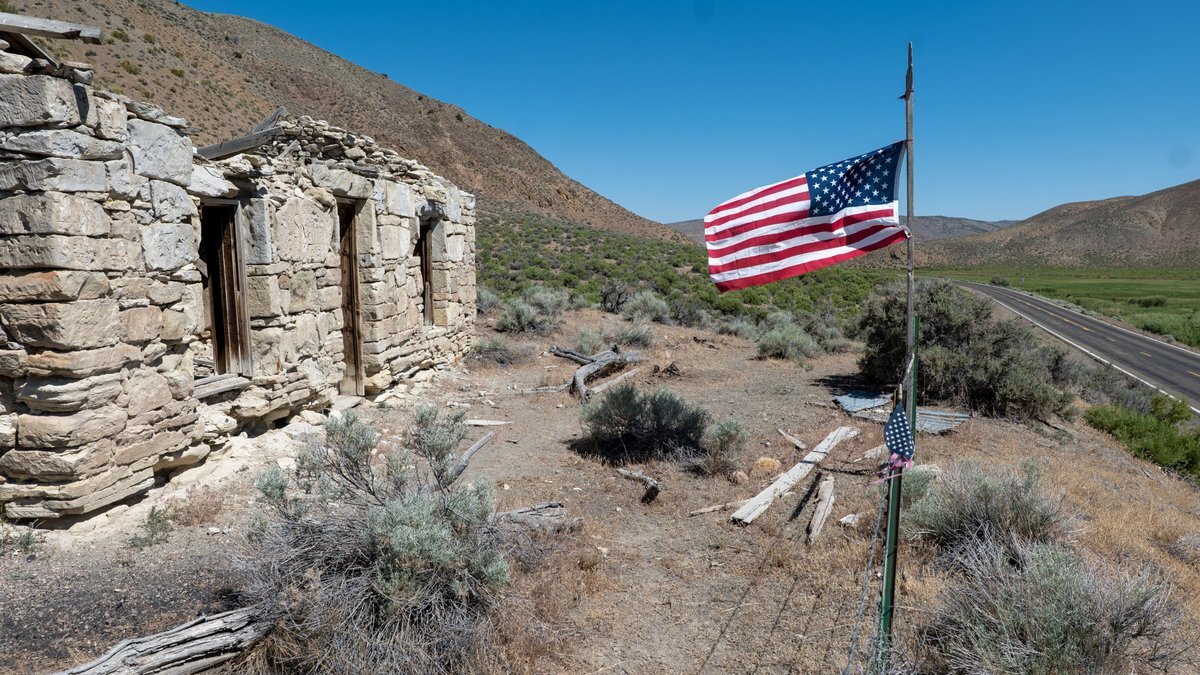 A ruined stone building beside a lonely desert road with an American flag flying