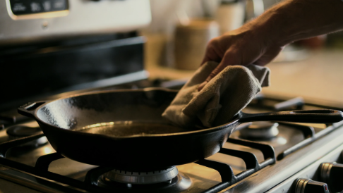 Cast iron skillet being wiped clean on a stovetop