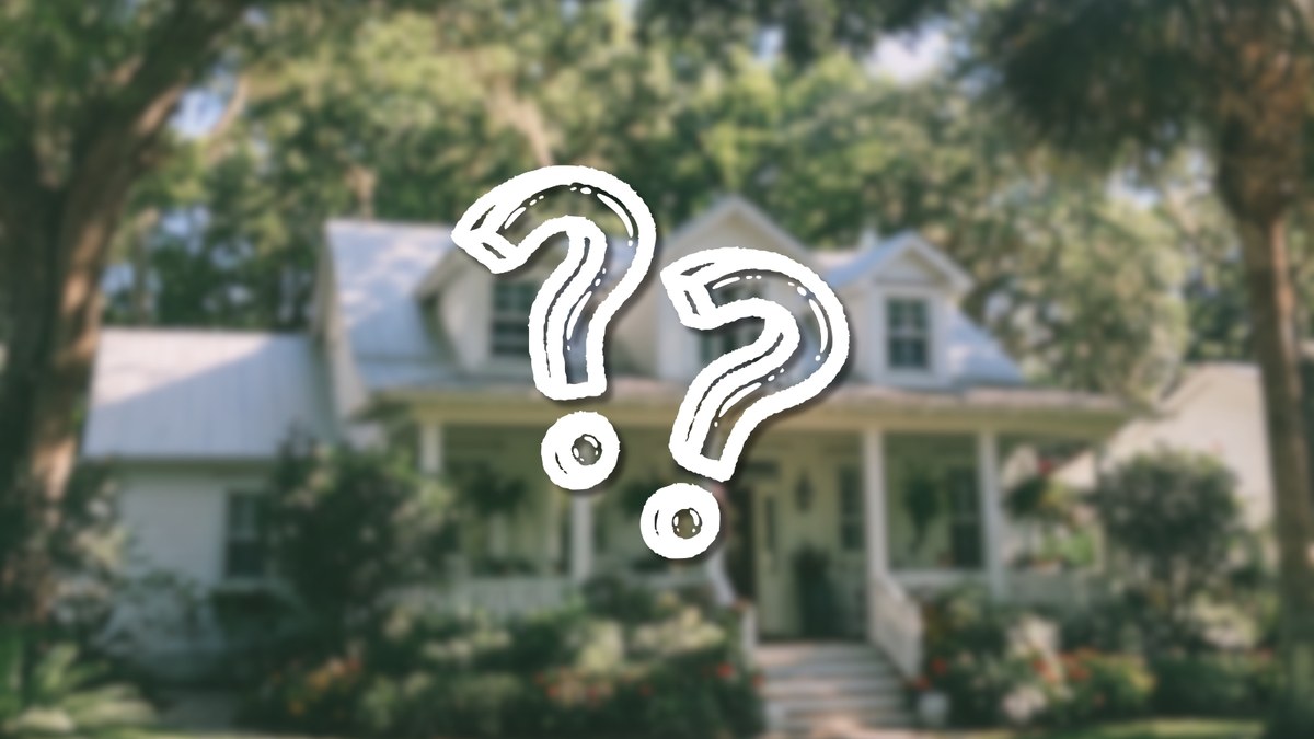 A blurred white house behind two large question marks