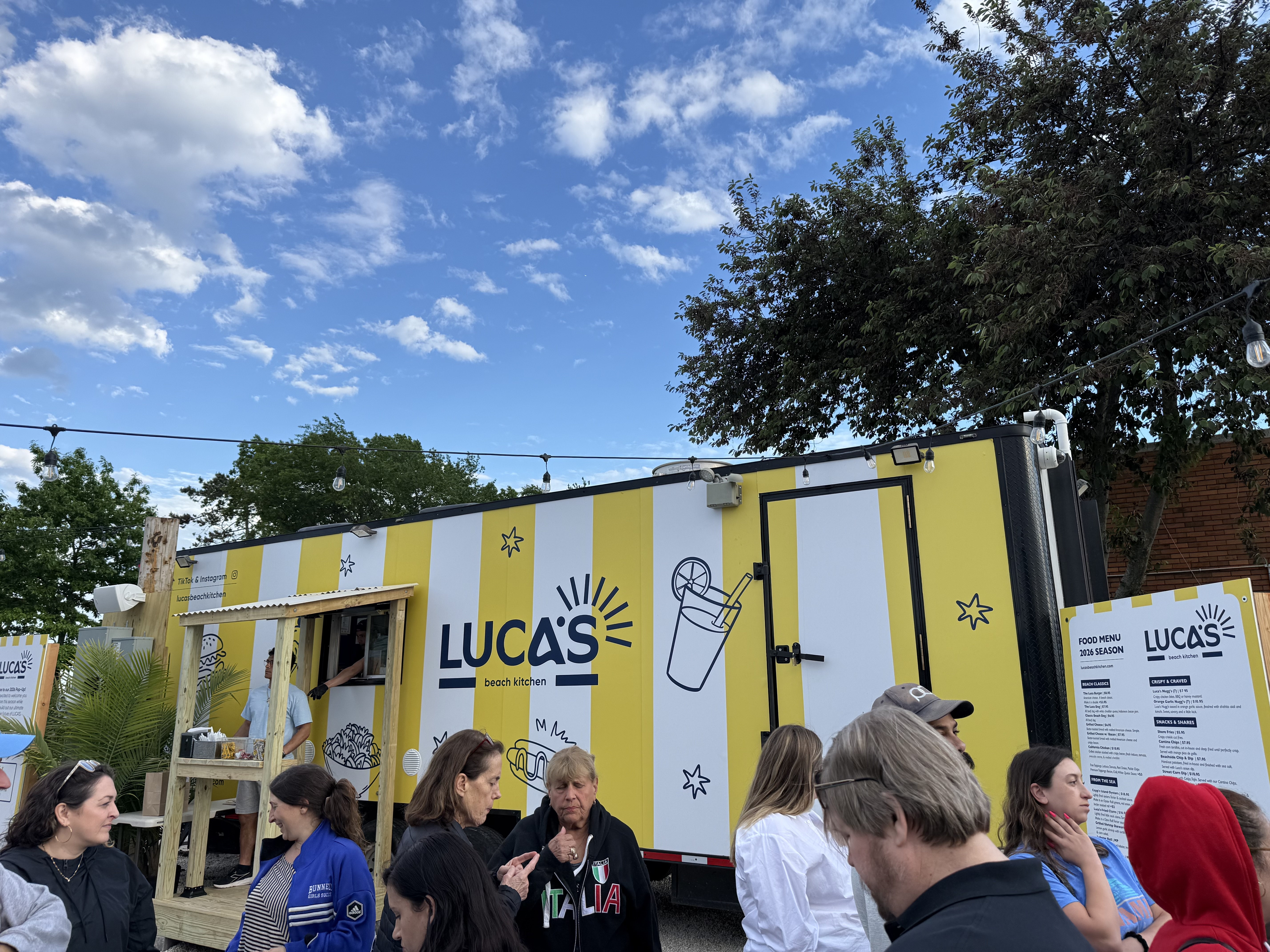The Luca's Beach Kitchen trailer with the wordmark logo and menu board displayed beside it.