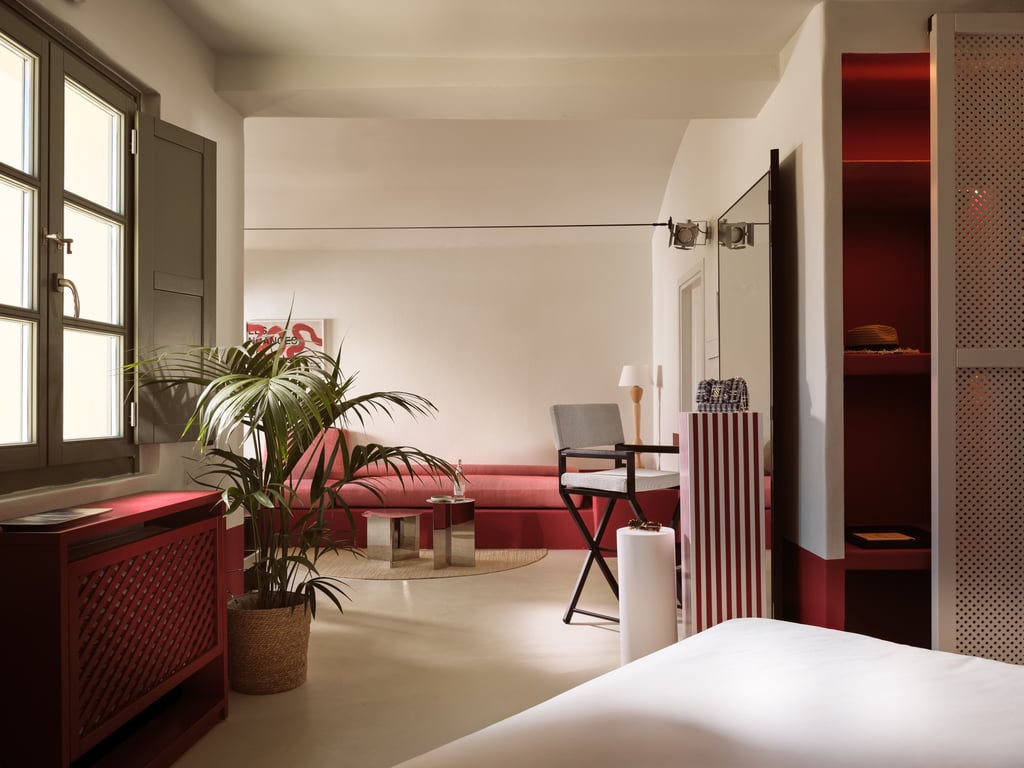 Fashion-forward suite with white walls, red cabinetry, and a leafy potted plant