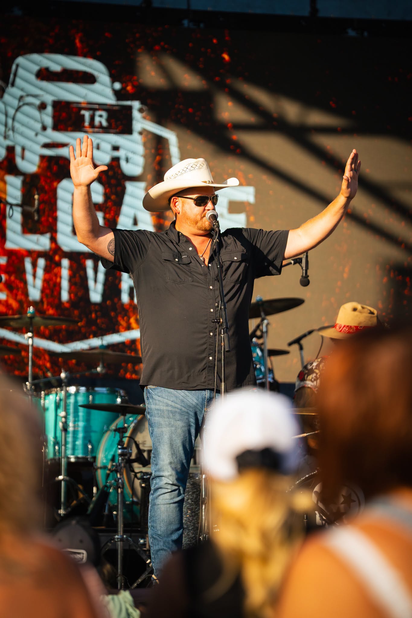 Tailgate Revival frontman with arms raised on stage