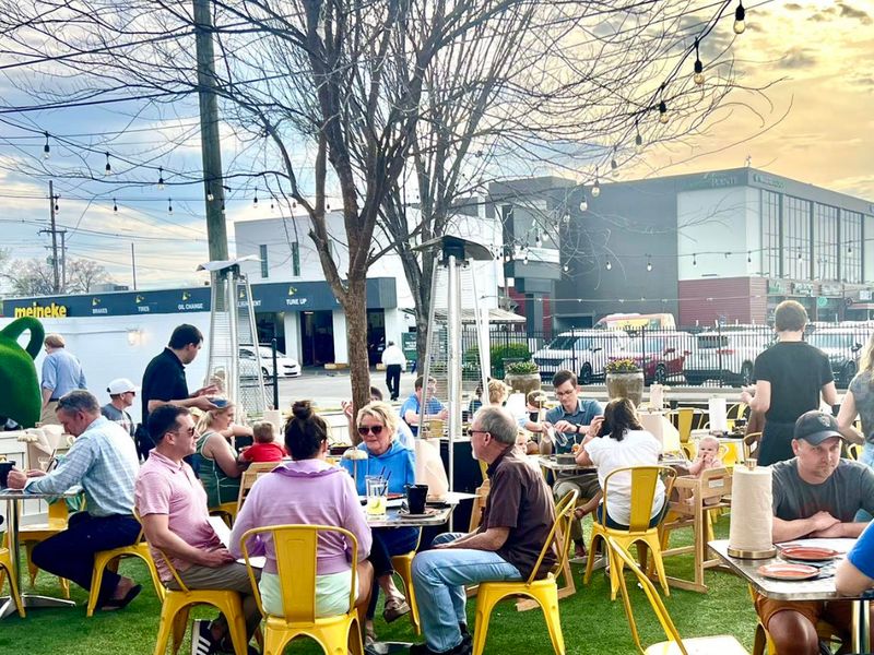 Turf patio with yellow chairs under string lights at Bourbon & Burgers