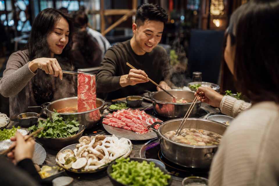 Friends sharing a do-it-yourself hot pot dinner at Piping Hot in Richmond BC