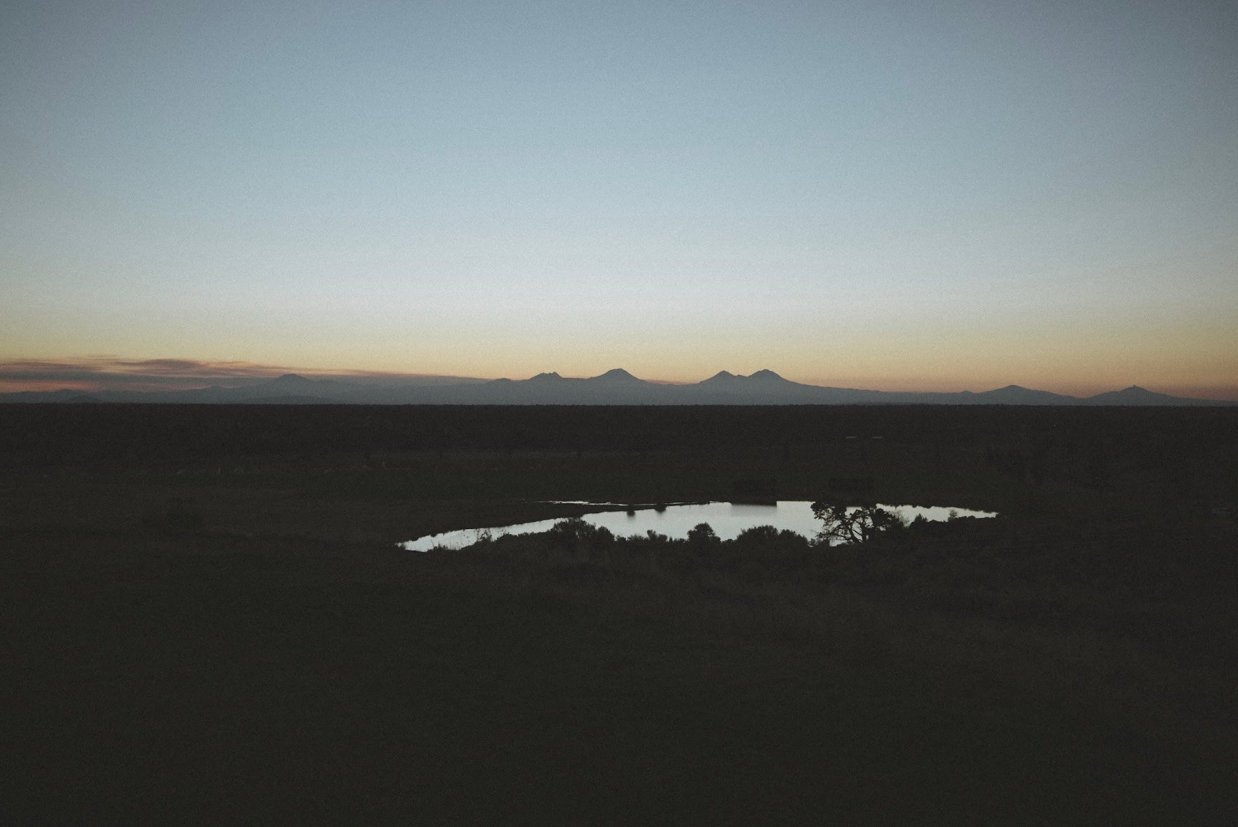 Mountain silhouettes and a pond at sunset in Central Oregon