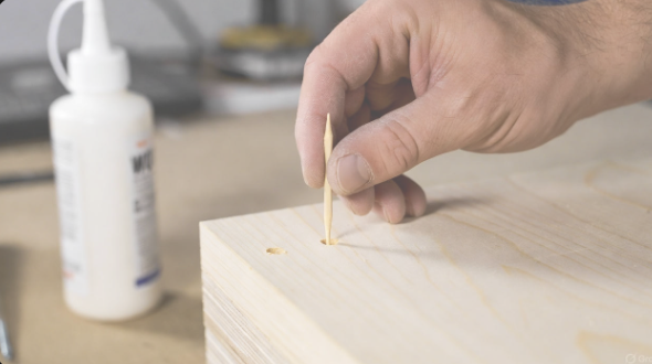 Wooden toothpick being inserted into a stripped screw hole