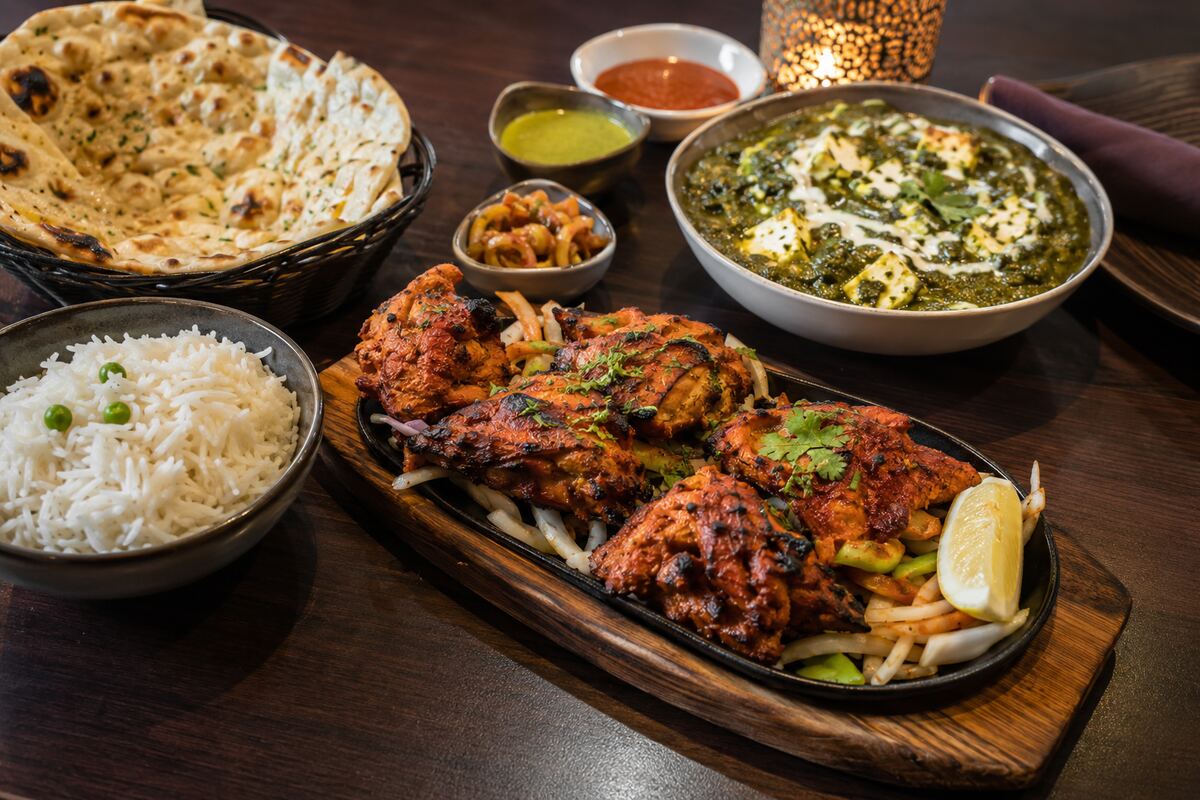 Indian dinner spread with tandoori chicken, saag paneer, basmati rice, naan and chutneys