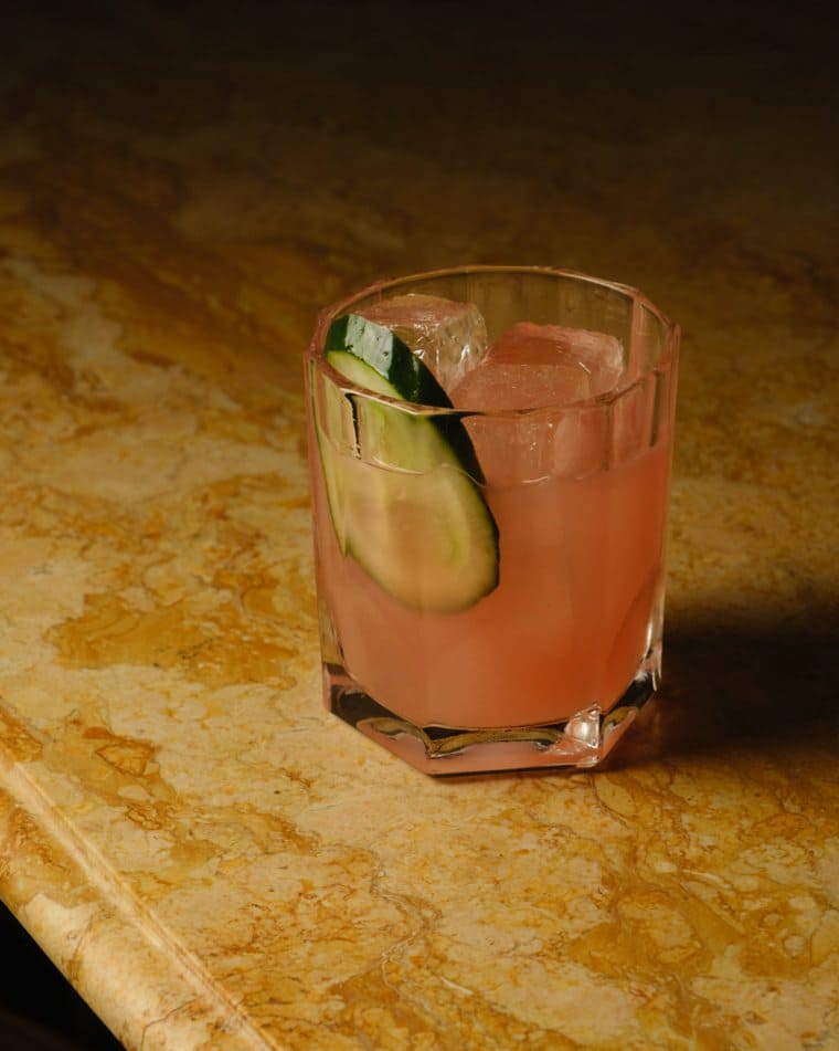 The house cocktail at A La Renaissance in Paris, pale pink with cucumber, on a marble bar