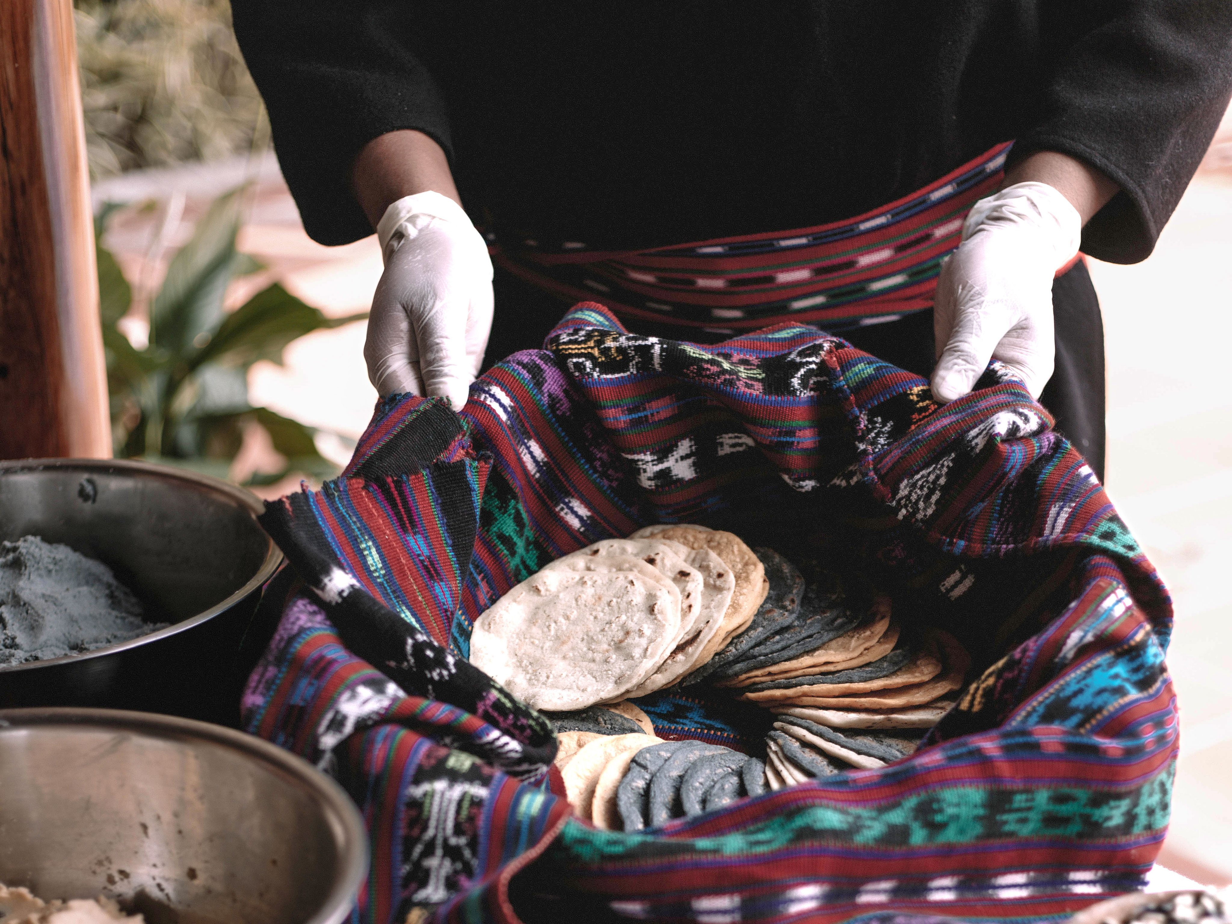 Hands preparing fresh tortillas in a woven Guatemalan cloth