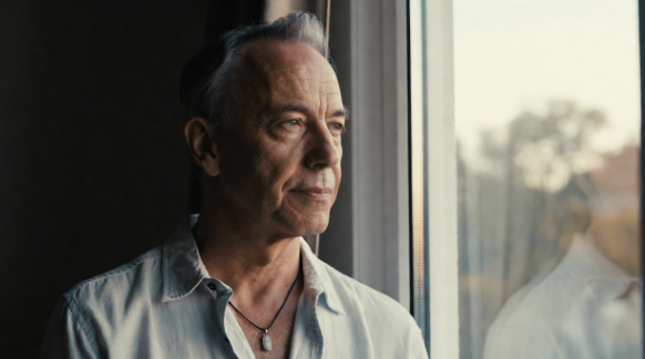 Man looking out a window into the distance to rest his eyes