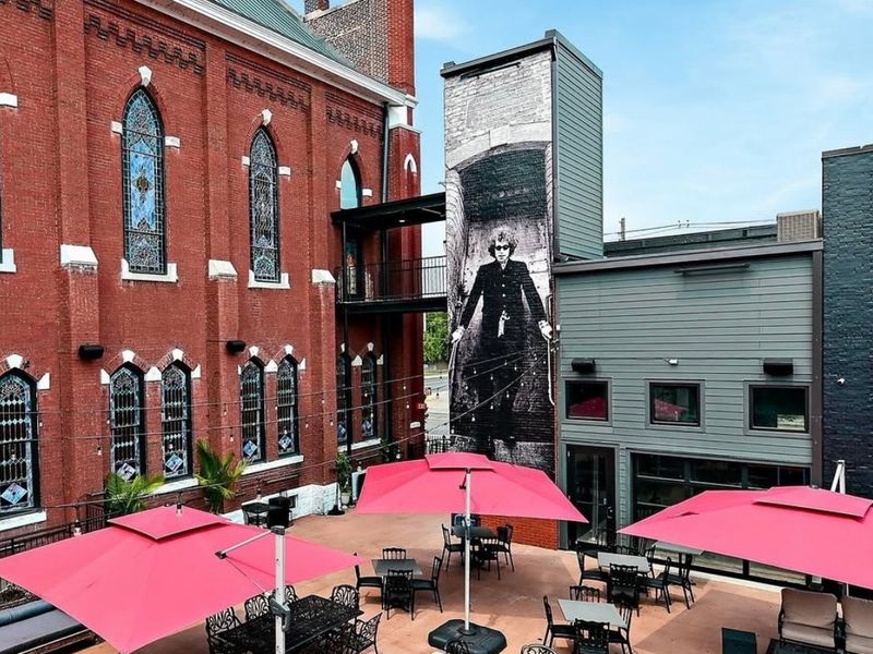 Patio with pink umbrellas beside a red-brick church at The Last Refuge