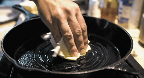 Cast iron skillet being oiled for seasoning