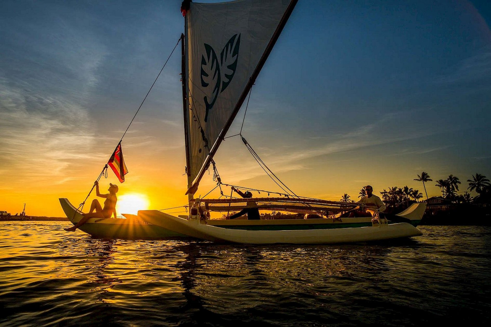 Outrigger sailboats on the water at sunset