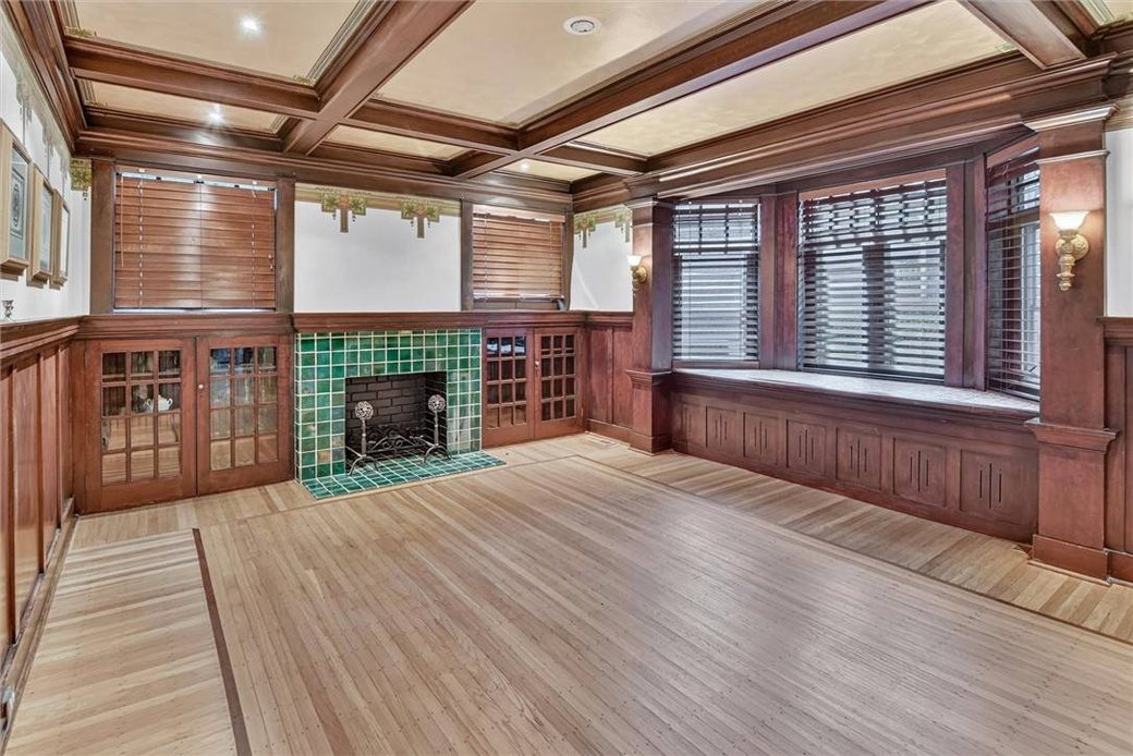 The den at 1321 Beechwood Boulevard: coffered ceiling, glass-front built-ins, a green tile fireplace and a window seat