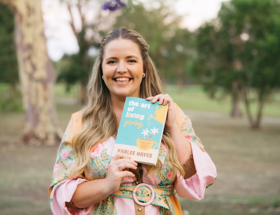 Karlee Hayes smiling outdoors holding The Art of Giving