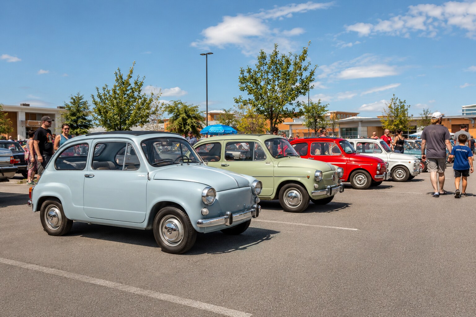 Families walking past a row of colourful vintage compact cars at an outdoor car gathering