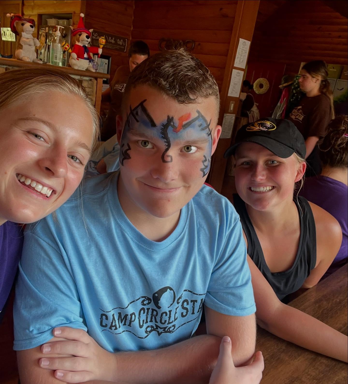 Camp Circle Star camper with face paint and volunteers