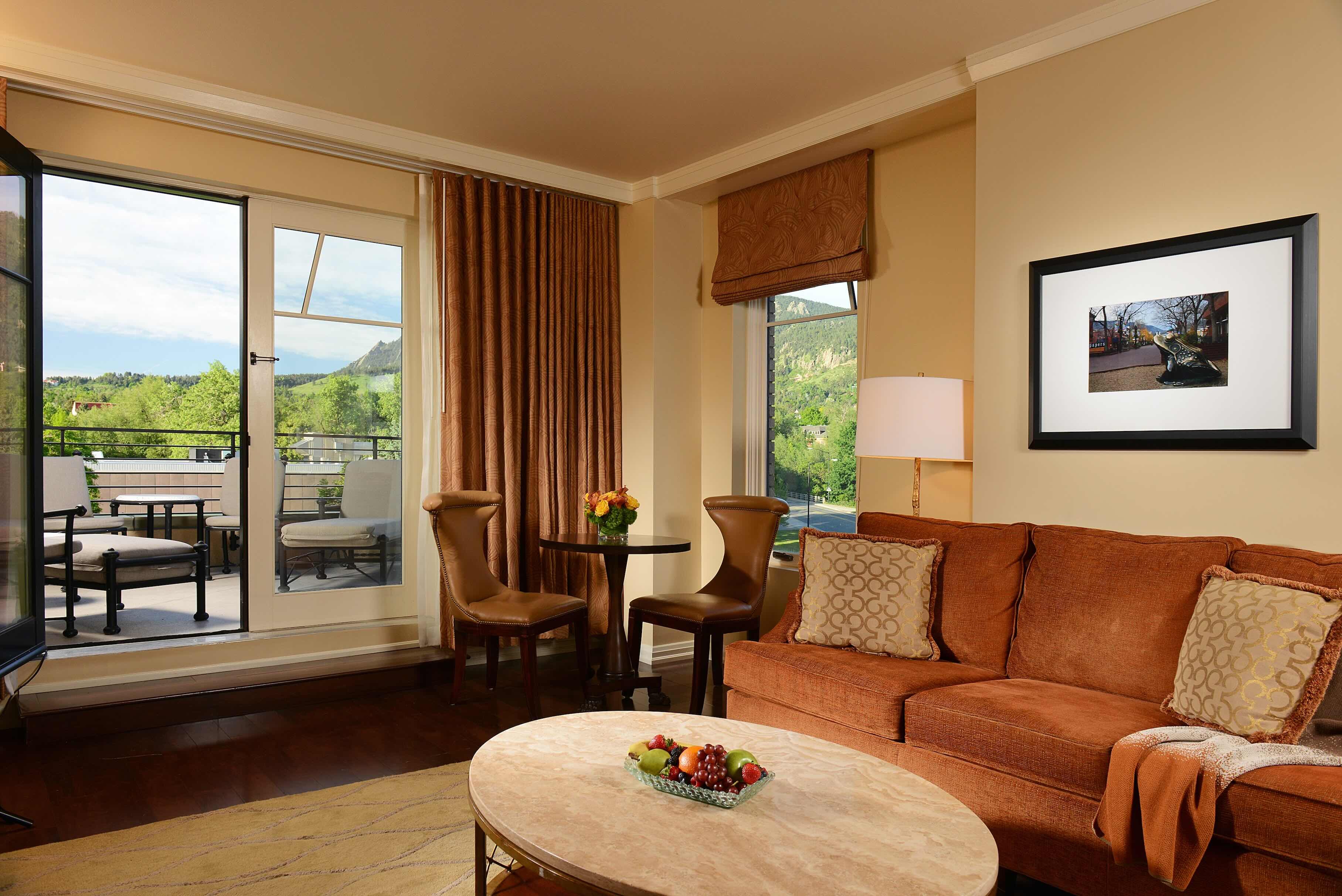 Suite sitting area with an orange sofa and doors to a mountain-view terrace