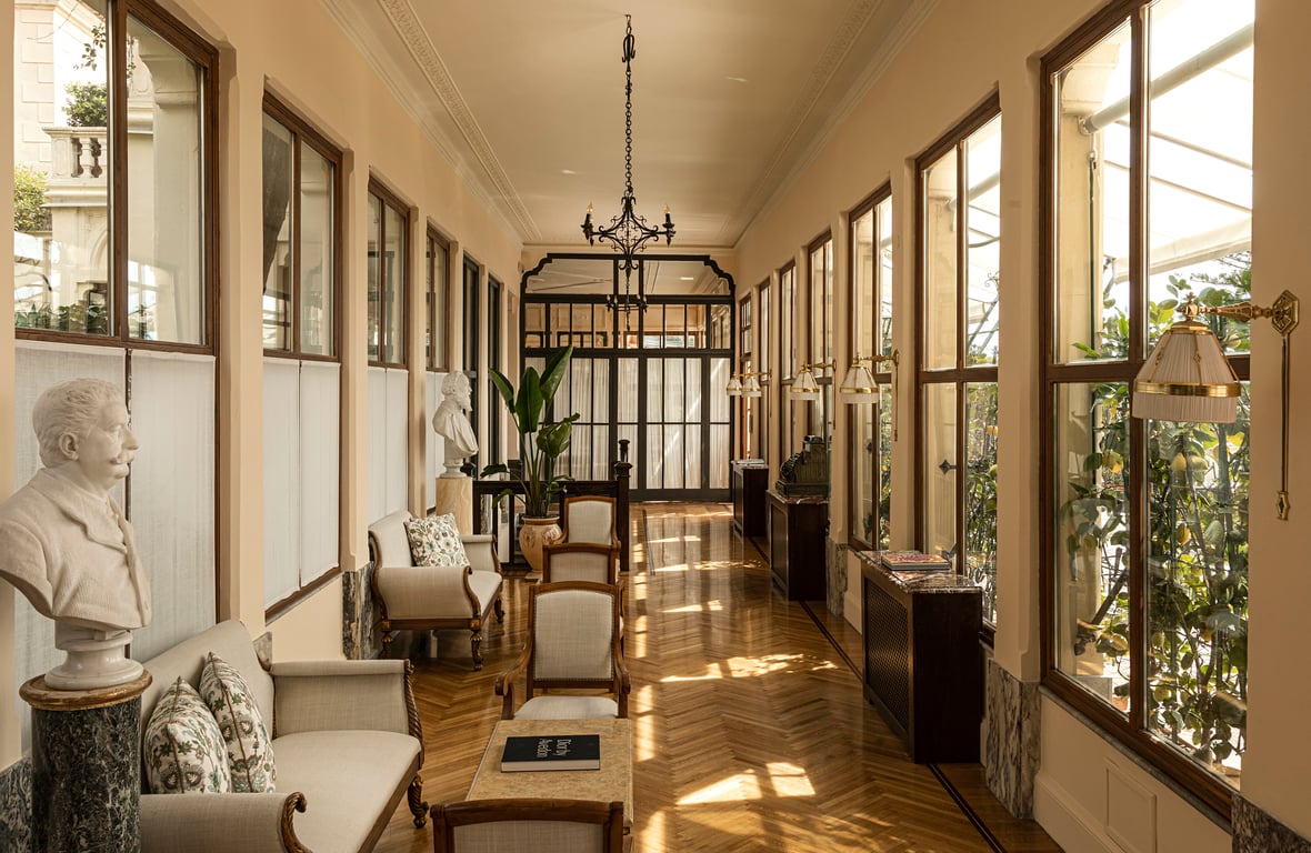 Elegant corridor with tall windows, antiques, and polished floors
