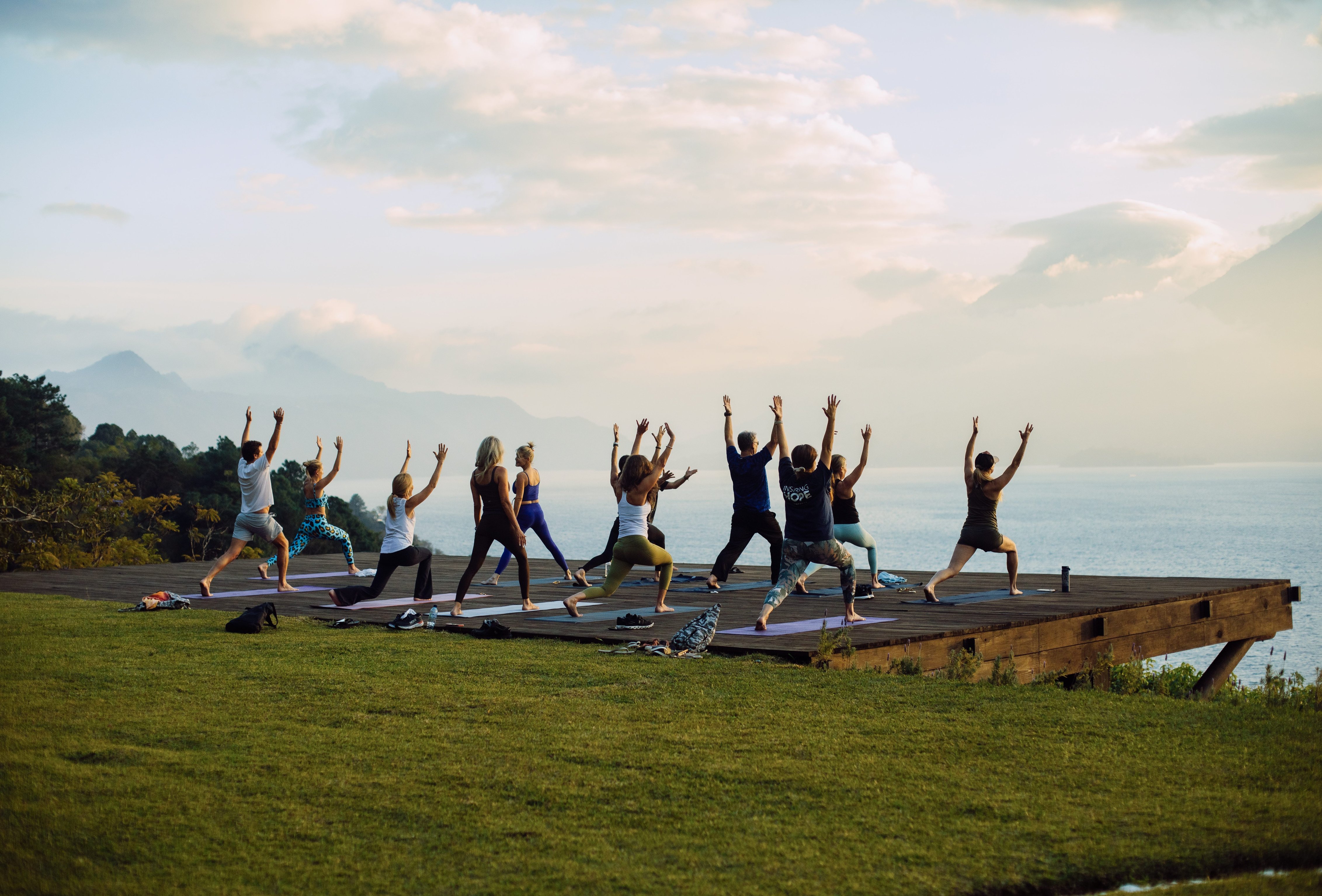 Guests practicing yoga on a lawn overlooking Lake Atitlán and the volcanoes