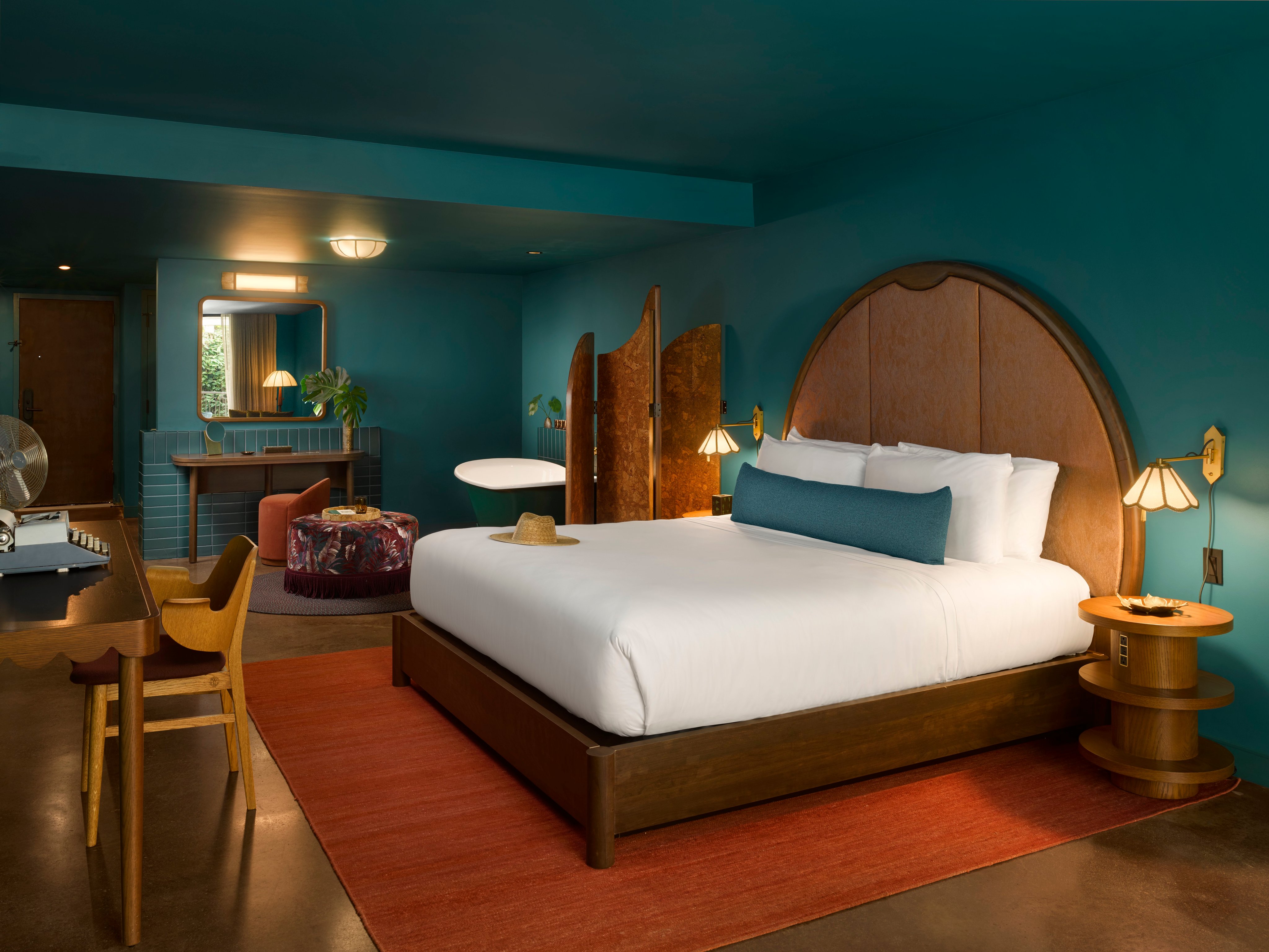 Guest room with teal walls and a curved wooden headboard at Mayfair House Hotel and Garden