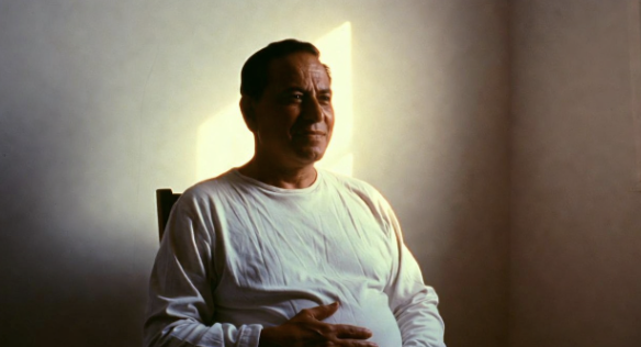 A calm man sitting upright with one hand on his belly, practicing slow breathing