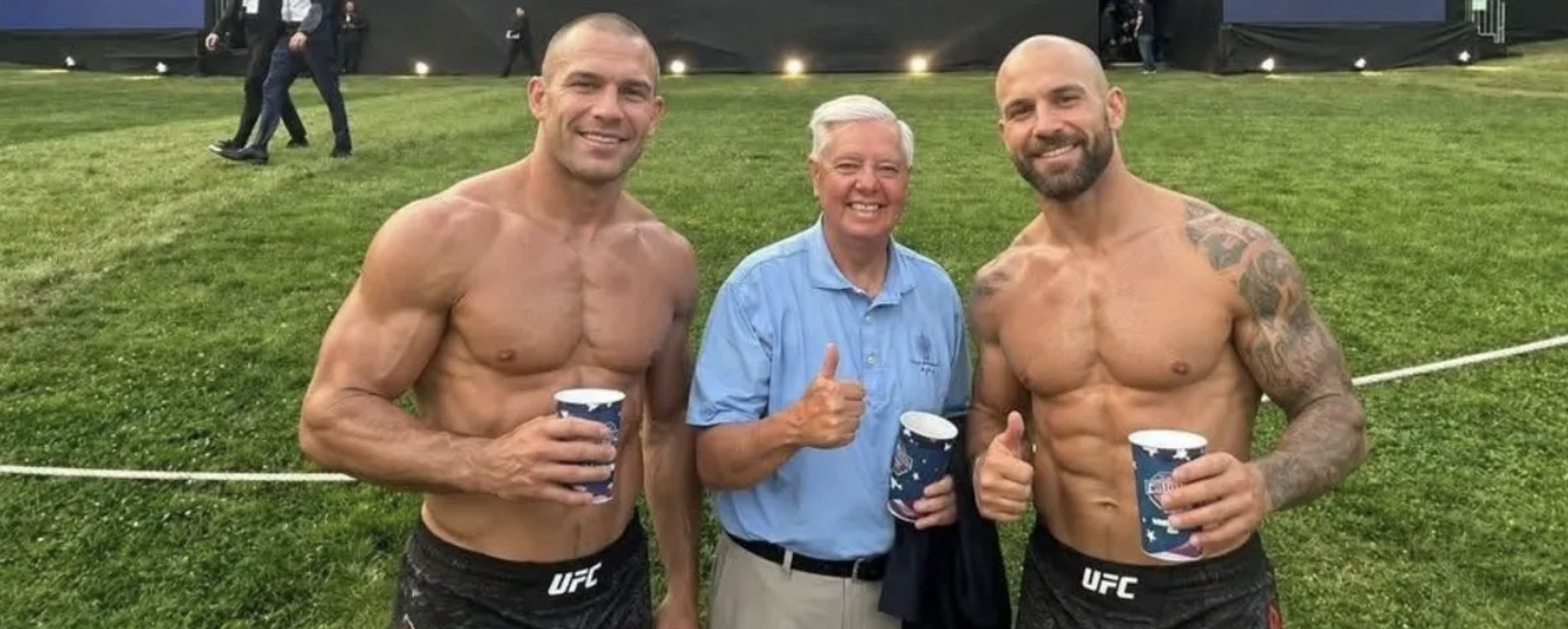 Sen. Lindsey Graham grinning between two impossibly smooth shirtless men who were wearing suits ten minutes earlier