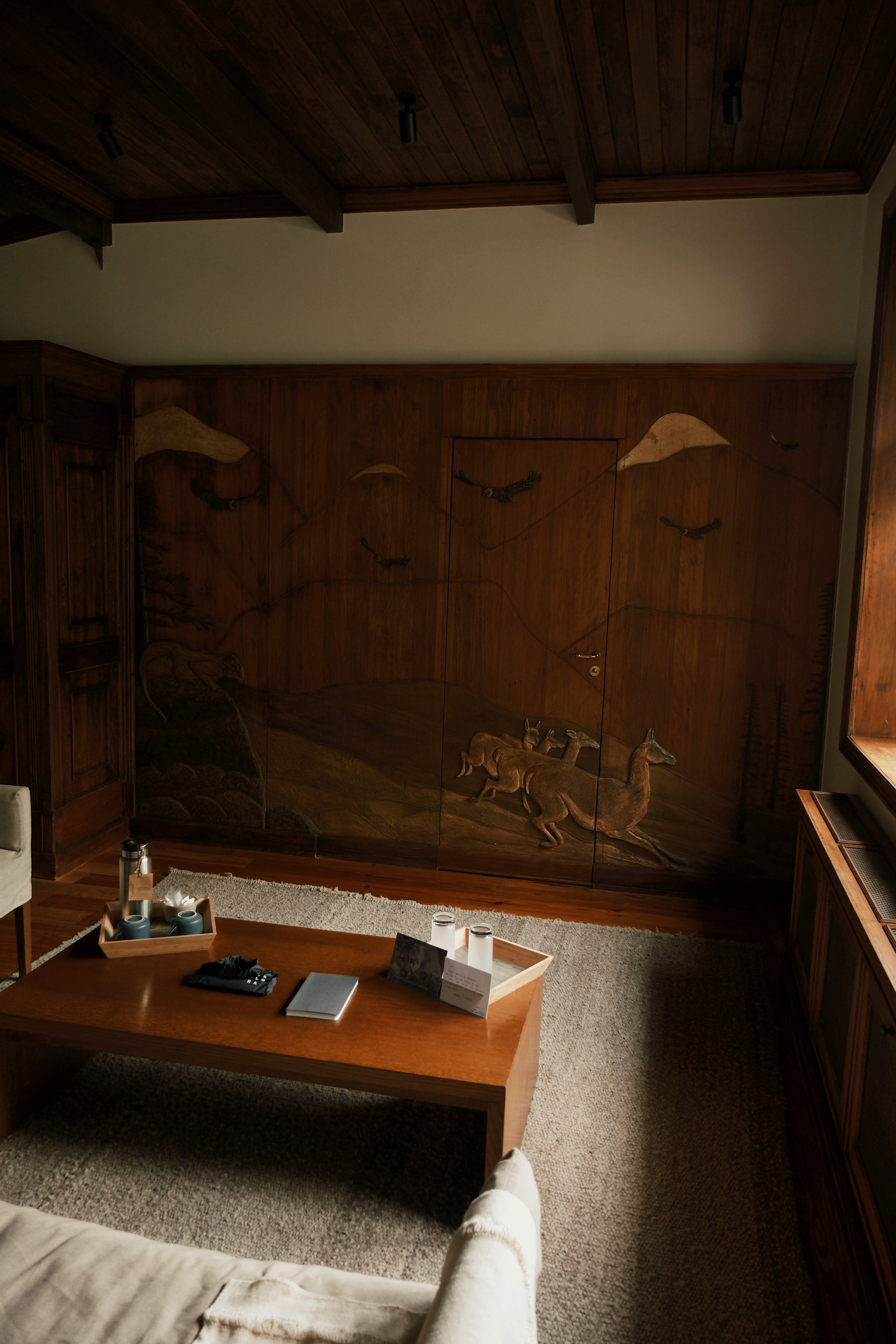 Carved wood wall and sitting area in a suite at Explora Patagonia National Park Lodge