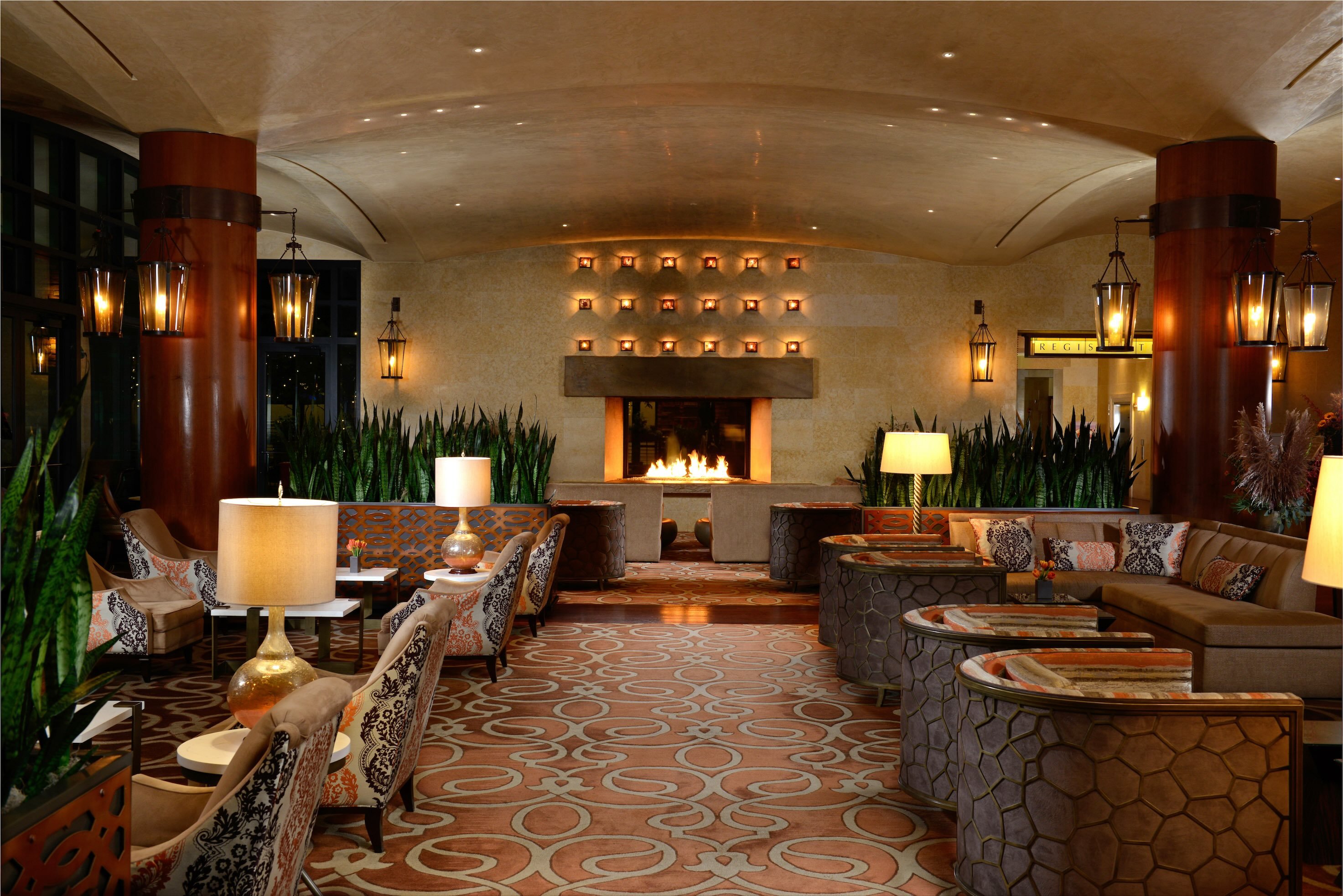 Warmly lit hotel lounge with sofas and a central fireplace