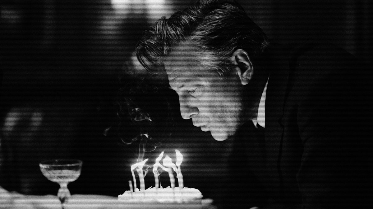 A birthday cake with lit candles in a darkened room