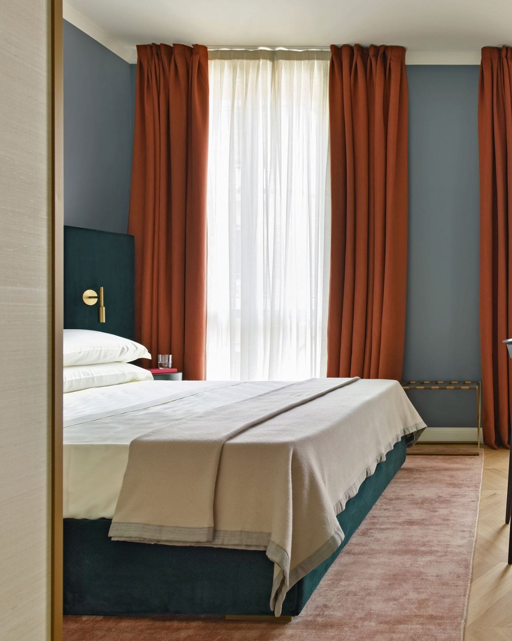 Casa Brivio guest room with teal walls and rust-colored curtains