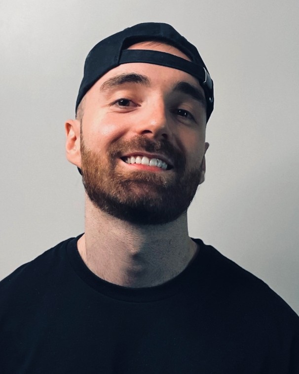 Portrait of Chris Watson in a backwards cap against a plain grey background