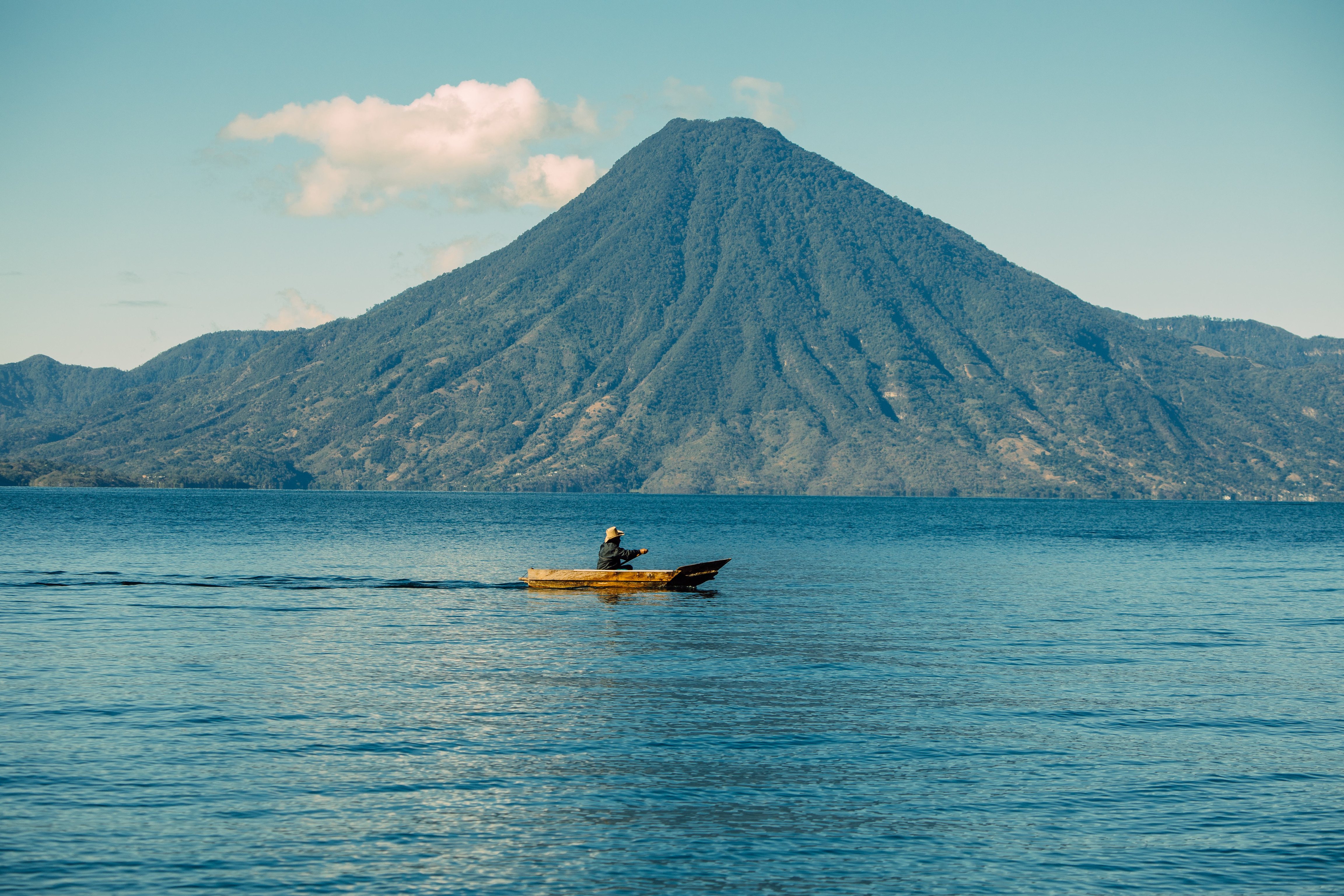 Kayaker crossing Lake Atitlán beneath a steep Guatemalan volcano