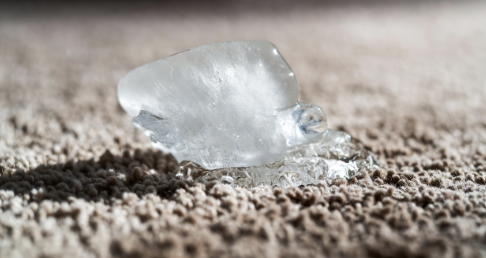 Close up of an ice cube melting on a carpet dent
