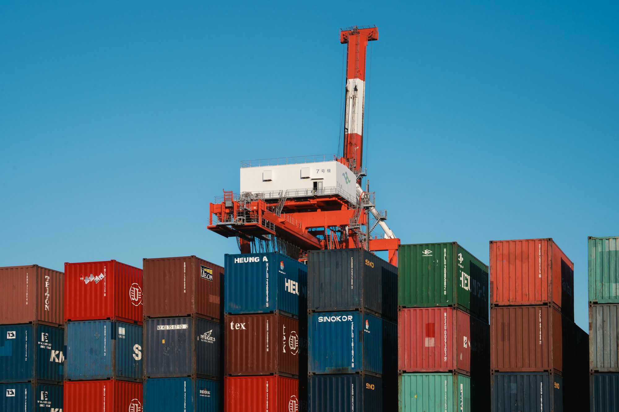Crane on top of a large stack of shipping containers