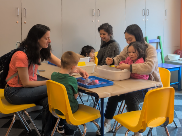 Adults and children exploring activities at a table in the museum's Mini Mingle promotional photo